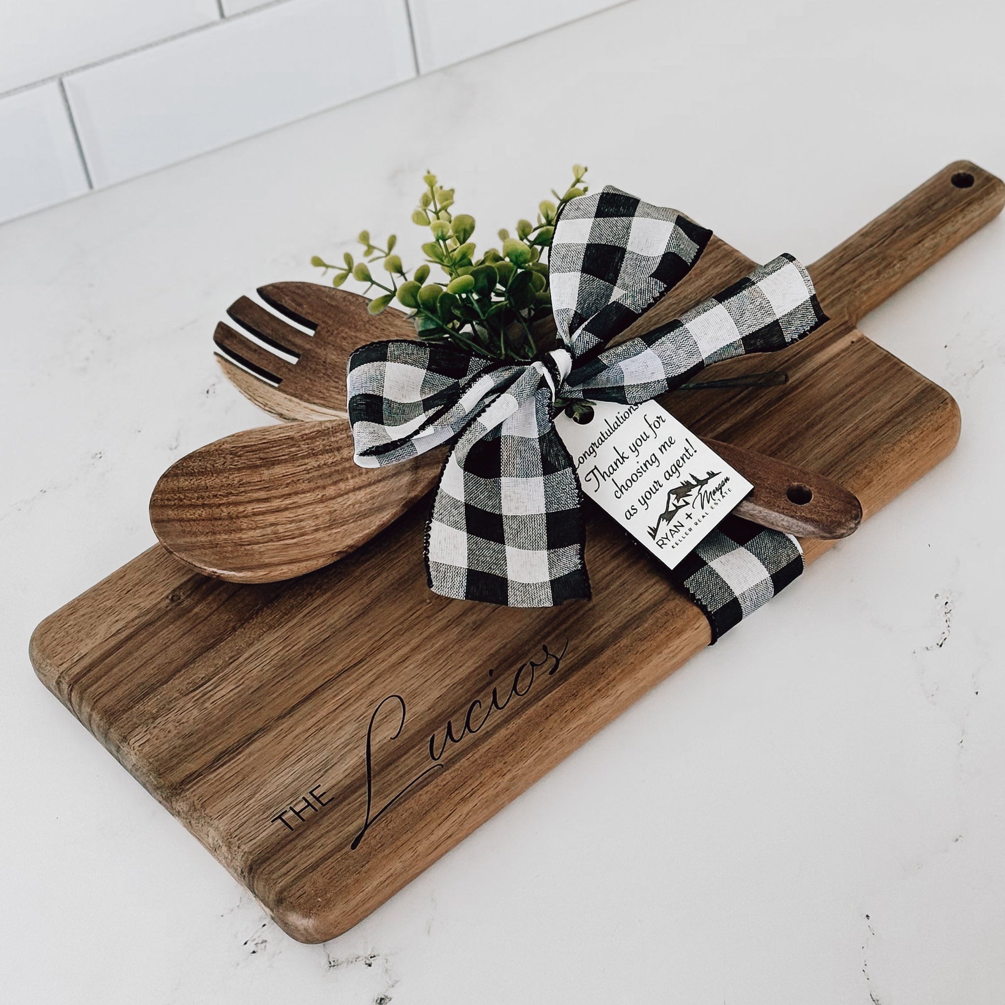 Real Estate Closing Gift 
Wooden cutting board with utensils and a bow on a marble surface
