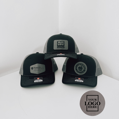 Realtor branded black and charcoal trucker snapback hat with gray circle patch with black engraving 