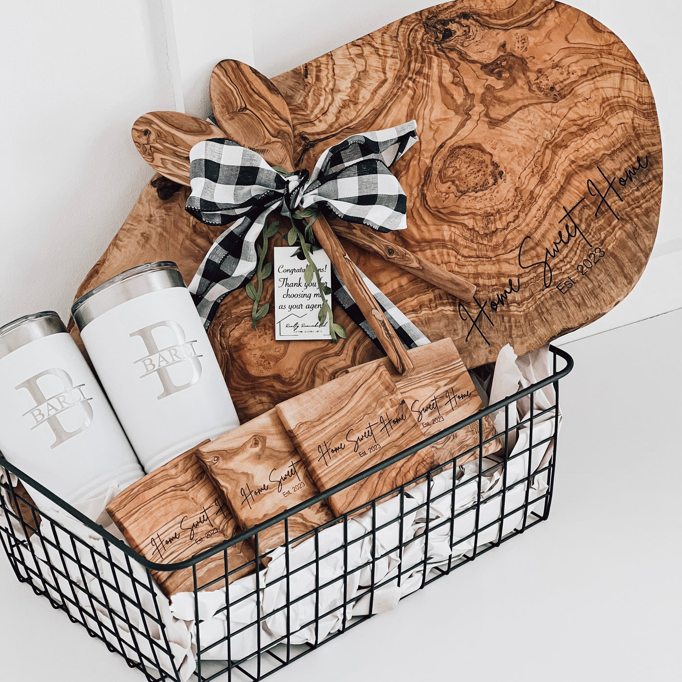 Real estate gift of a large olive wood gift basket including a large olive wood board and matching coasters with design 1 and 2 20 oz tumblers with design 2 on them 