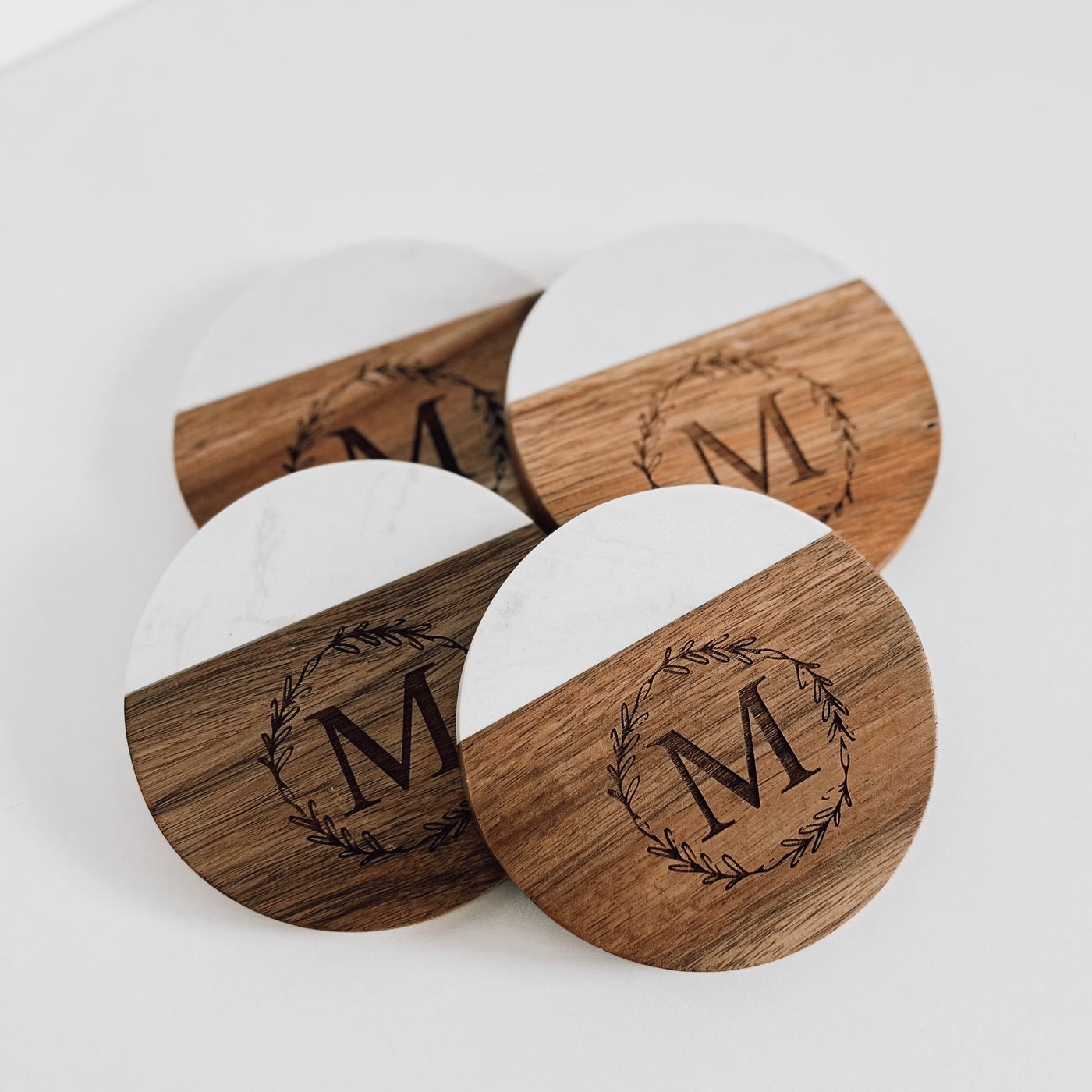 Real estate gift of round coasters with design 2 of last initial inside a circle wreath