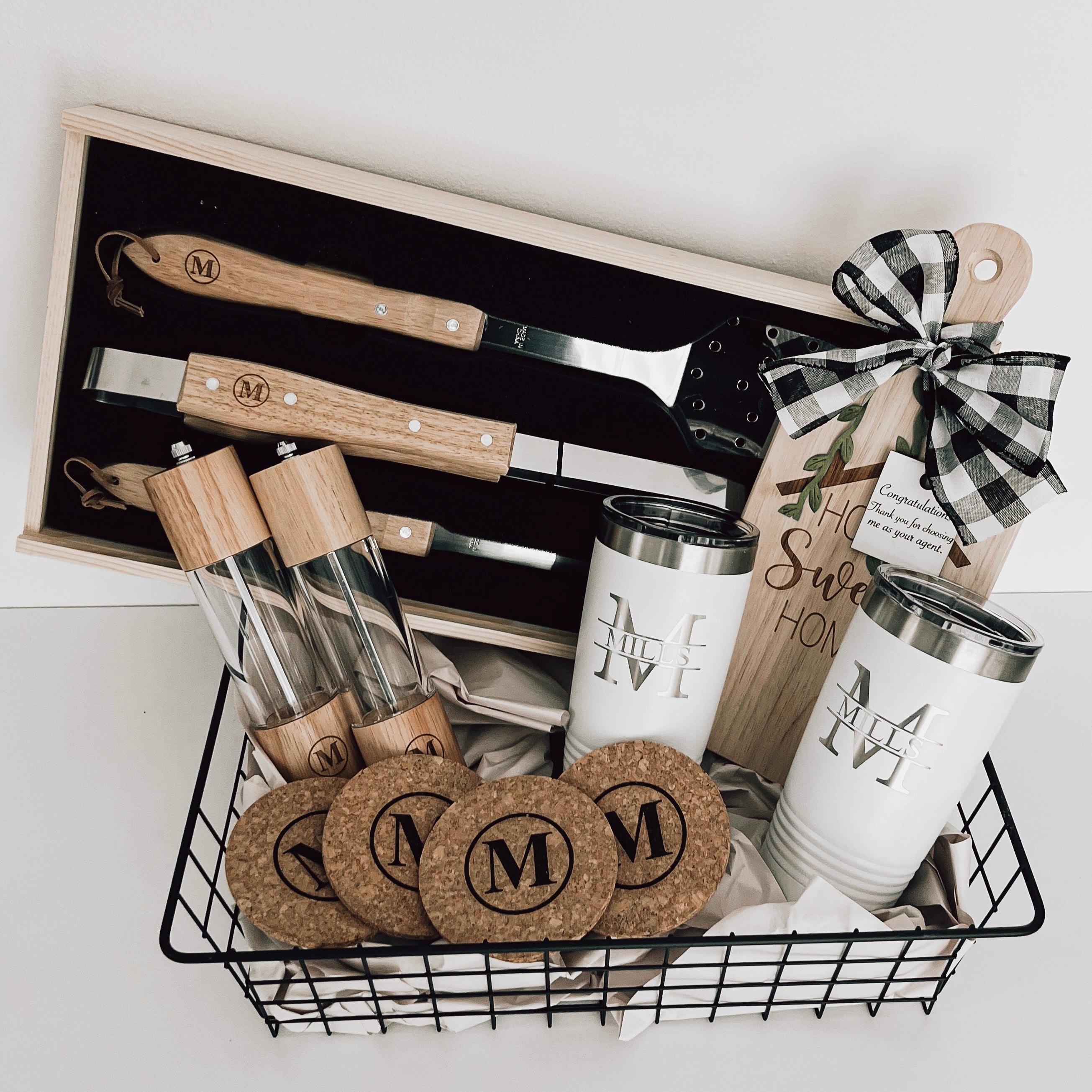Real estate gift of grill basket showing the inside of the tools that includes salt and pepper shakers, cork coasters, small rubber wood board, and 2 20 oz tumblers