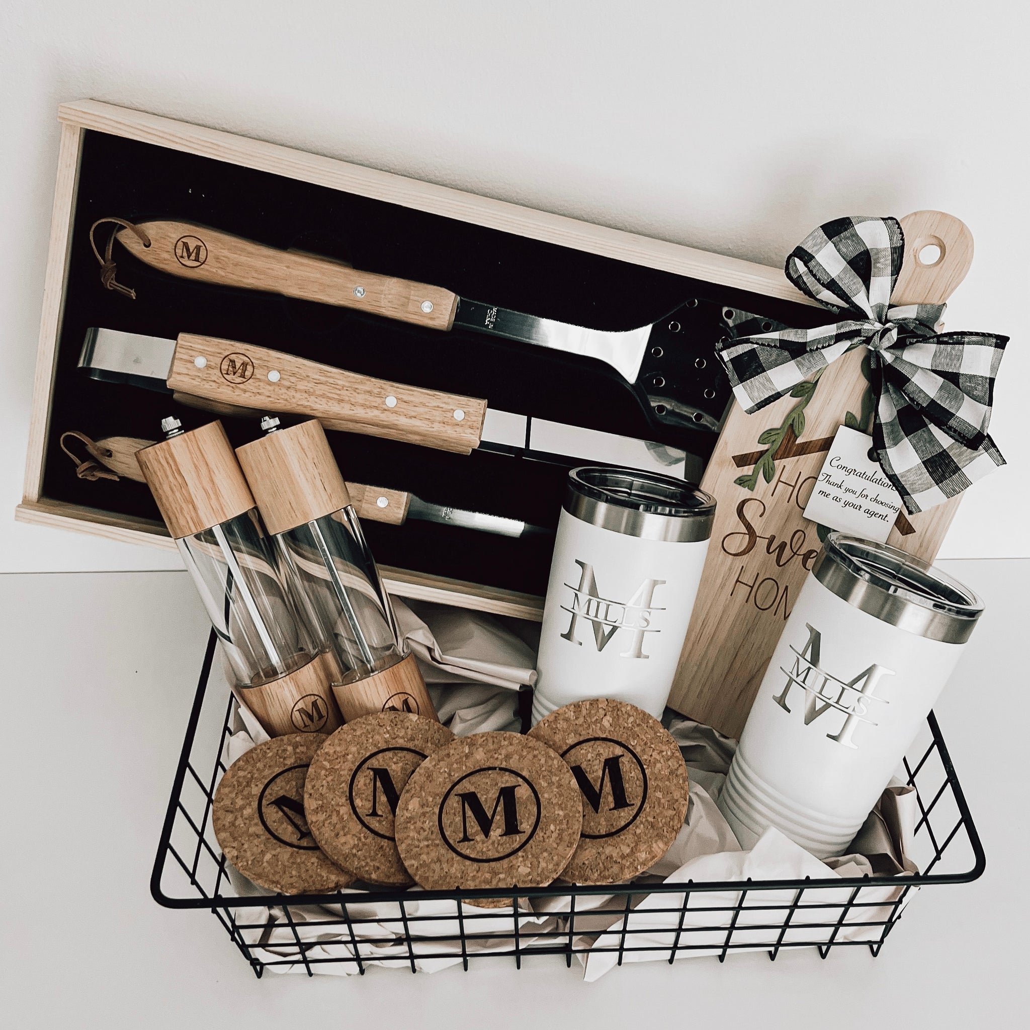 Real estate gift of grill basket showing the inside of the tools that includes salt and pepper shakers, cork coasters, small rubber wood board, and 2 20 oz tumblers