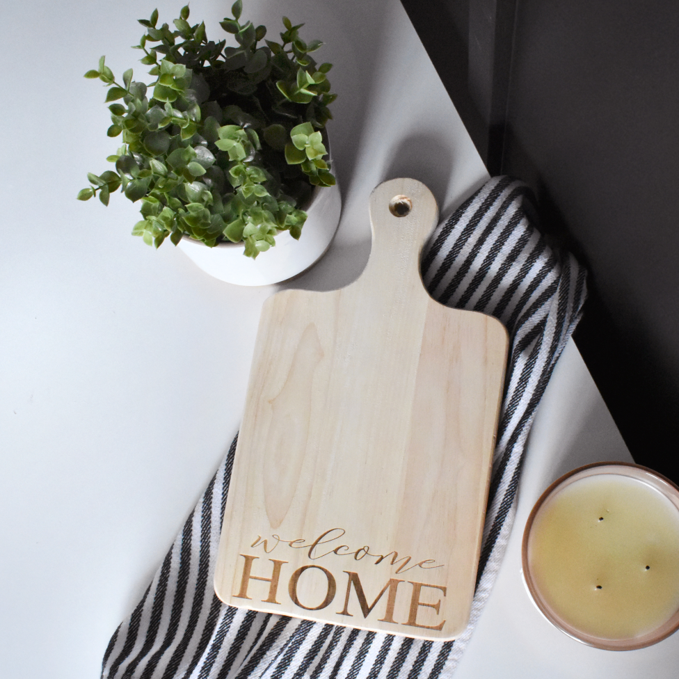 Real estate gift of a medium paddle cutting board made of rubber wood with welcome home design