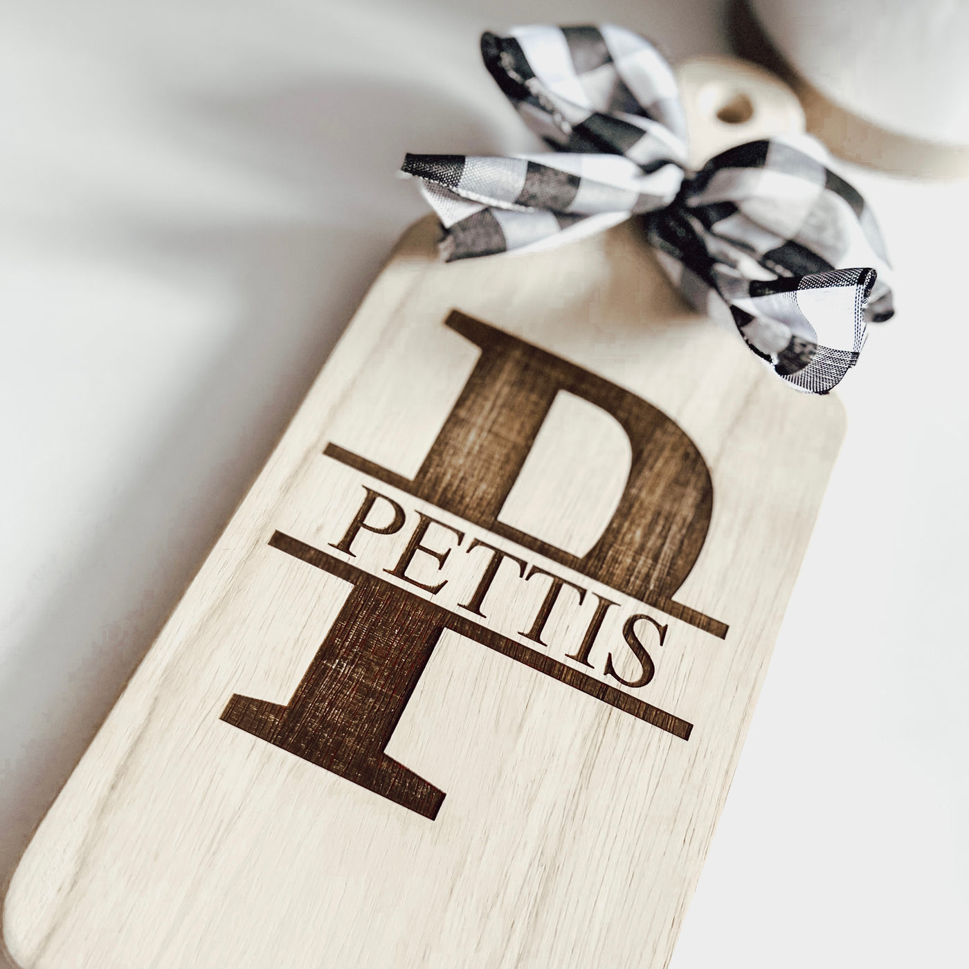 Real estate gift of a small paddle cutting board made of rubber wood with split monogram design 